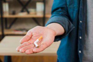 Tangan pria memegang rokok patah, gambaran hipnoterapi berhenti merokok Bali