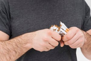 Pria mematahkan rokok dengan tangan sebagai simbol hipnoterapi berhenti merokok Bali