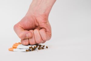 Tangan menggenggam dan menghancurkan rokok, simbol kekuatan hipnoterapi berhenti merokok Bali